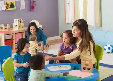 معلمة تساعد أطفالاً في نشاط تعليمي داخل المركز